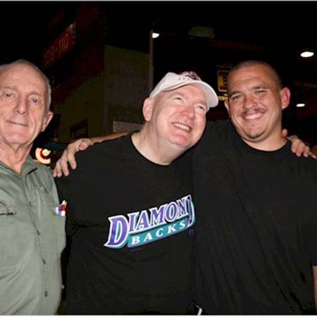 A picture of three men smiling for the camera. The man on the left is Jim Goodson, one of VCD’s founders, and he is wearing a green shirt. The man in the middle is Edward Reis wearing a black shirt with the word diamondbacks on the front of it. Richard Vanover is on the right wearing a black shirt.